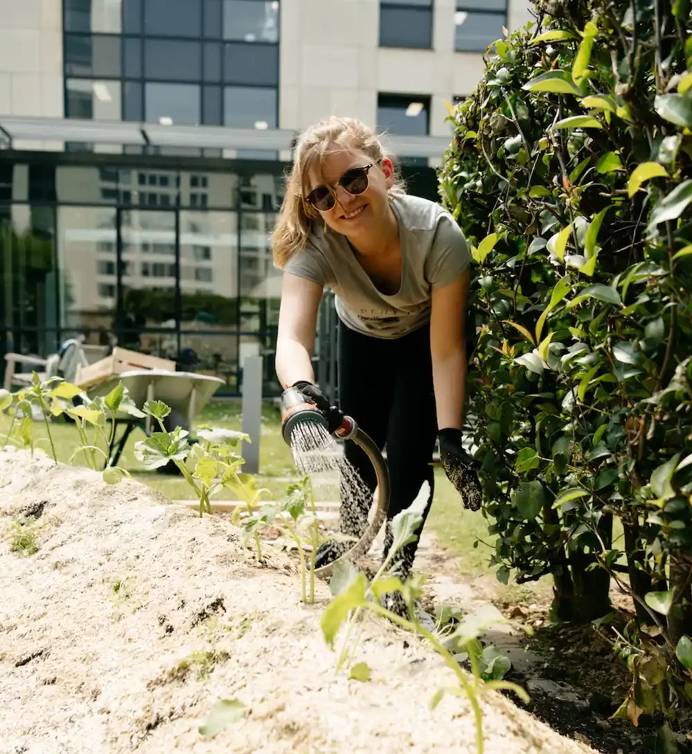 Participante arrose les plantes au potager du Groupe M6